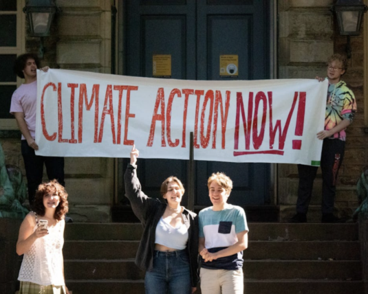 Young activists in front of a protest sign that says 
